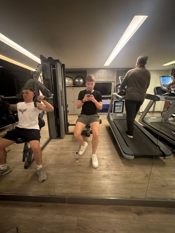 A gym scene featuring three individuals engaged in different workouts.