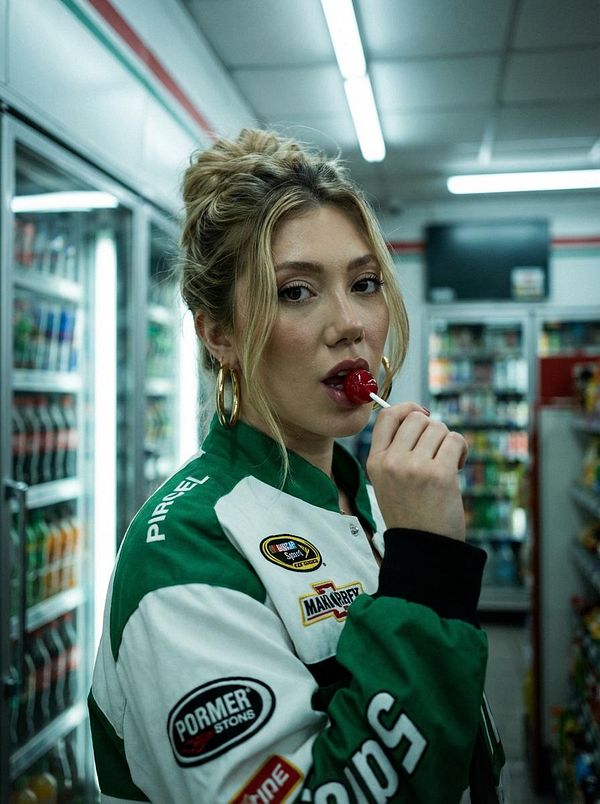 A close-up portrait of a light brown dog wearing black rectangular glasses.