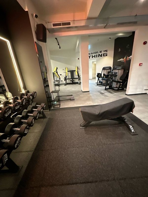 A modern gym interior featuring weights, exercise equipment, and motivational wall art.