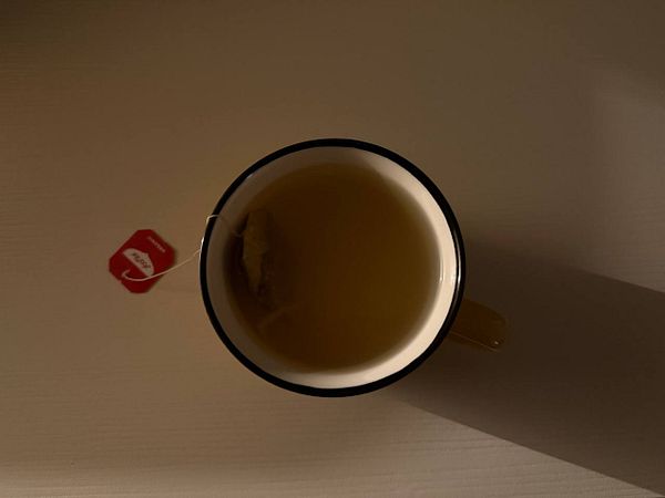 A cup of chamomile tea with a tea bag steeping in it.