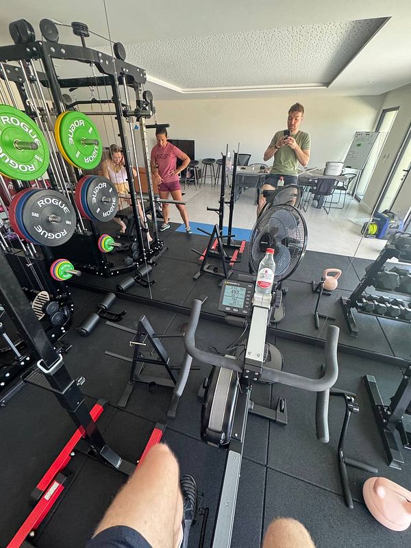 A home gym setup featuring various exercise equipment and individuals preparing for a workout.