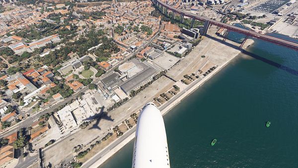 An aerial view of Lisbon with an A380 aircraft flying overhead, casting a shadow on the ground.