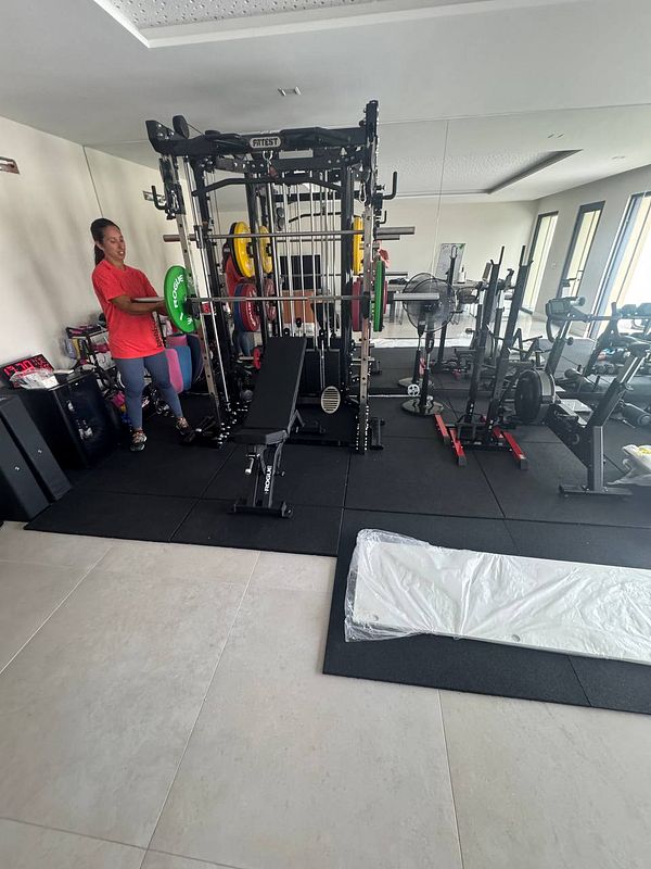 A personal trainer is preparing to lift weights in a well-equipped home gym.