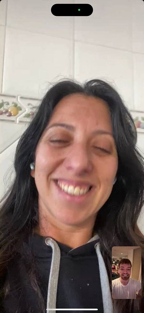 A woman is smiling while video chatting with a man on a mobile device.