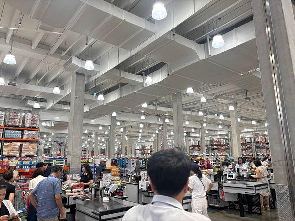 A busy Costco store filled with shoppers and checkout counters.