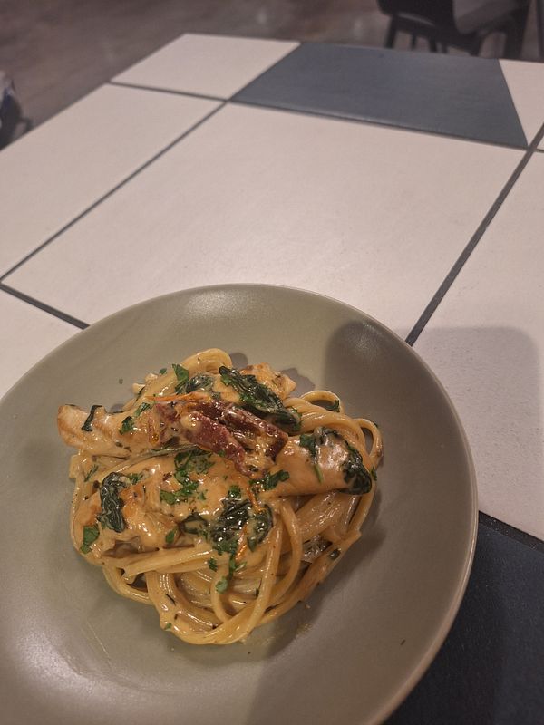 A plate of Tuscan chicken pasta is presented on a table.