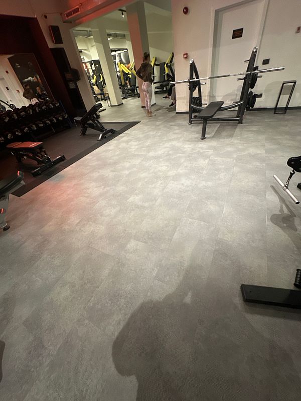 A gym interior featuring various workout equipment and a person preparing to exercise.