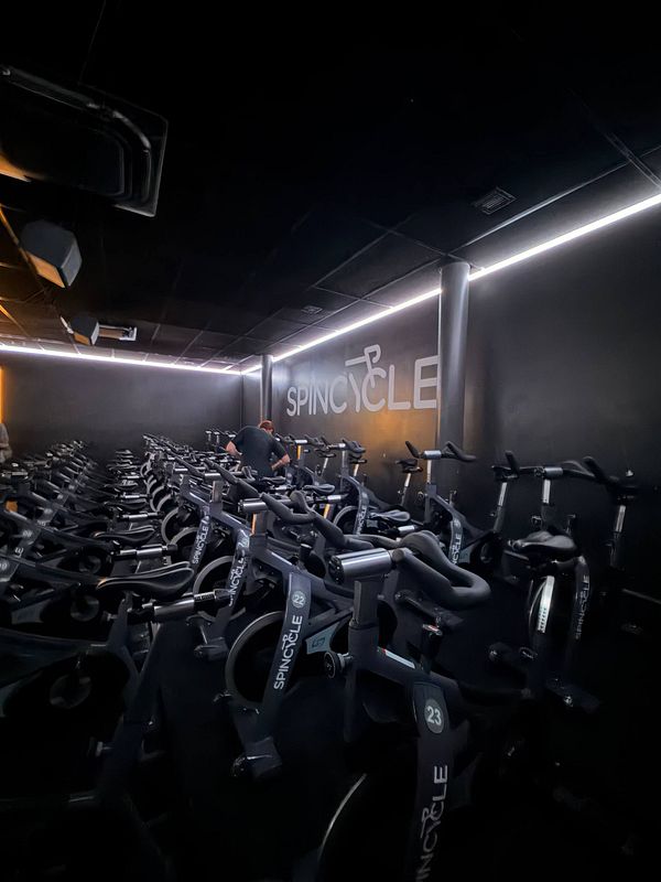 Photo of a modern gym interior with wooden floors, various fitness equipment, and large windows.