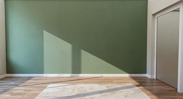 A minimalist interior space featuring a green wall and wooden flooring.
