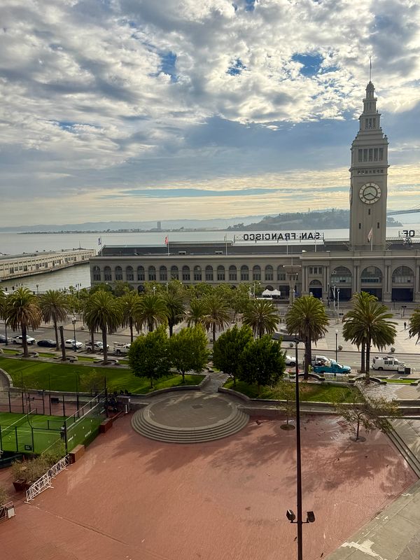 A bright sunny day in San Francisco with a view of a city skyline including the Bay Bridge and waterfront buildings.