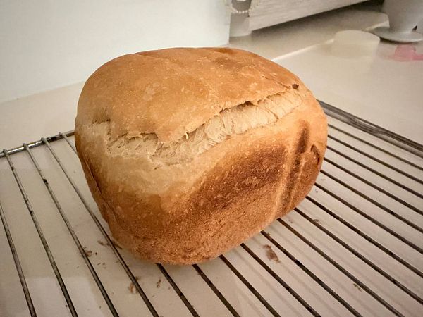 A freshly baked loaf of bread cooling on a wire rack.
