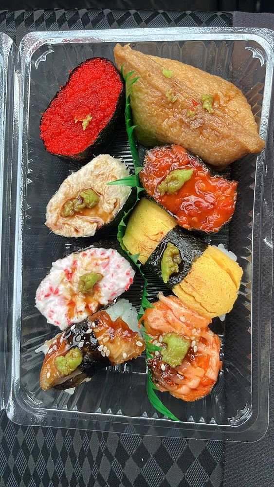 A variety of sushi pieces arranged in a clear plastic container.
