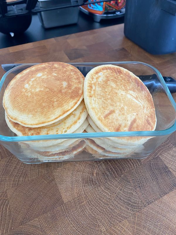 Close-up view of a plate with golden brown pancakes topped with syrup and butter on a table.