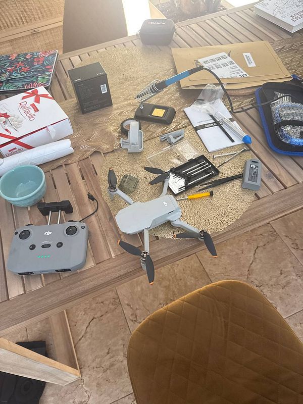 A workspace cluttered with drone repair tools and components.