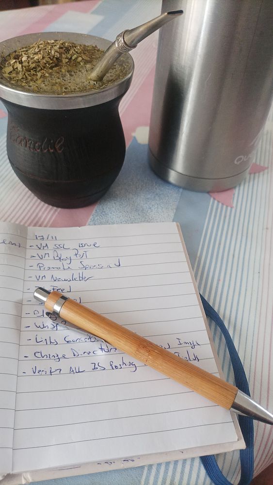 A cozy workspace featuring a traditional mate drink, a notebook with tasks, and a thermos.