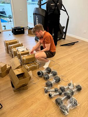 A person is assembling equipment for a home gym in a spacious room.