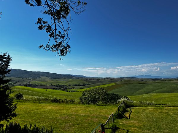 A picturesque view of the Tuscan countryside under a clear blue sky.