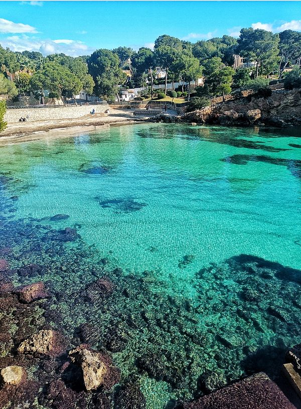 A serene coastal scene featuring clear turquoise waters and rocky shores.