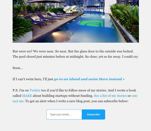 A rooftop pool area with lounge chairs and a city skyline in the background.