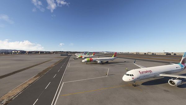 The image depicts a busy airport scene with multiple aircraft parked on the tarmac.