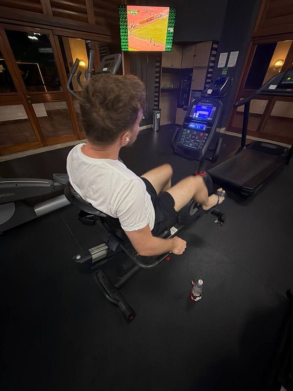 A photograph of a person lifting a barbell in a gym setting, wearing workout attire.