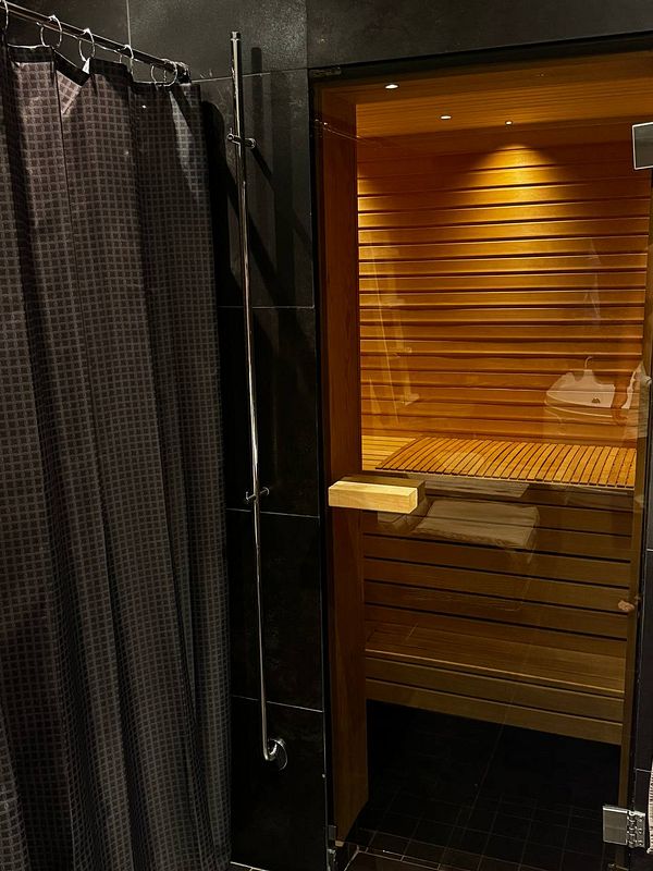 Photo of a sauna interior focused on a wooden bench and heater with stones.