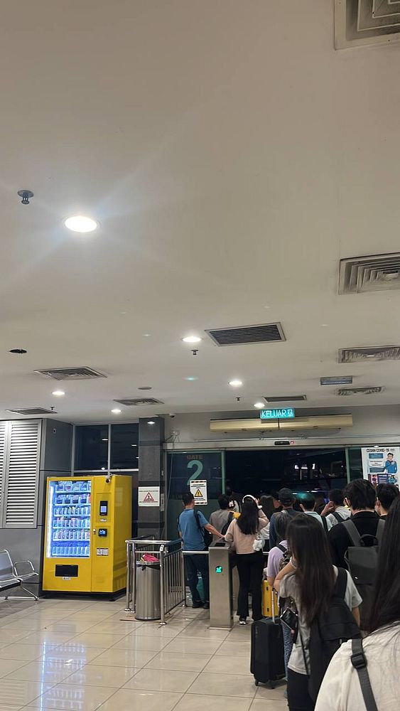A crowded bus terminal area with passengers waiting to board at Gate 2.