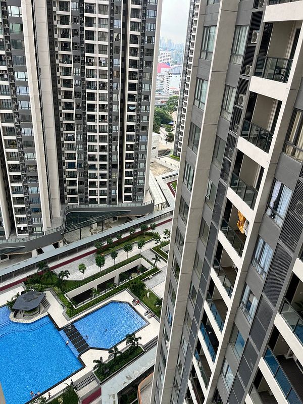 A view from a high-rise building overlooking a swimming pool and landscaped area in a residential complex.