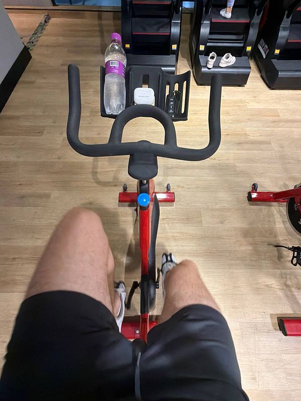 A gym environment featuring various cardio equipment including treadmills and stationary bikes with a focus on an empty treadmill in the foreground.