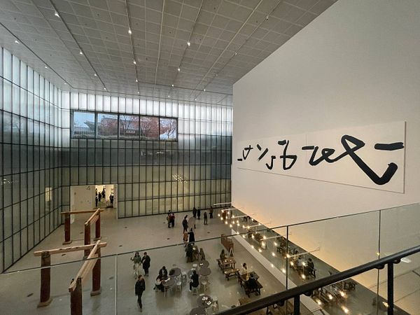 A spacious art gallery in Seoul featuring modern architecture and a large calligraphic artwork.