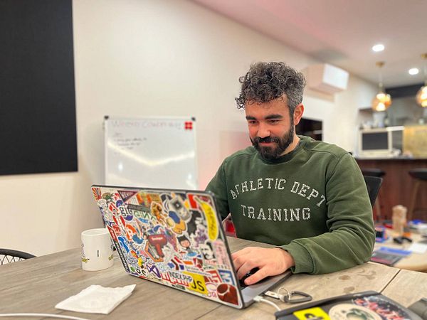A cozy coworking space setup with a laptop, coffee, notebook, and plant, designed for a productive remote work session.