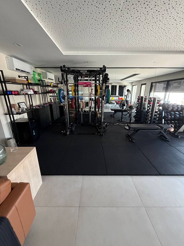 Gym locker room with wooden lockers and various gym attire hanging inside some lockers.