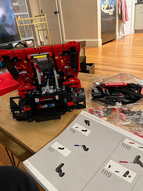 A partially assembled LEGO model is displayed on a table alongside building instructions and additional pieces.