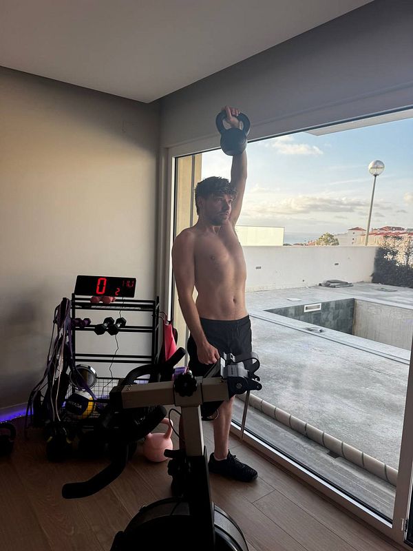 A man is performing a kettlebell exercise in a home gym setting.