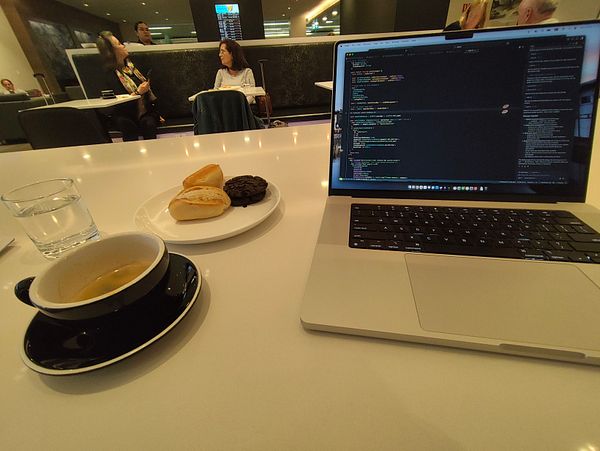 A workspace setup in the AirNZ lounge featuring a laptop, snacks, and a drink.