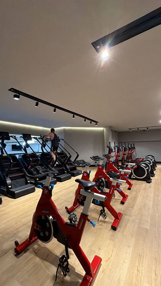 Photograph of a black and red gym bag and black sneakers on an asphalt surface with blurred greenery in the background.