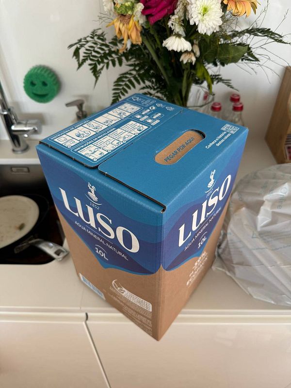 A 10L box of Luso mineral water is prominently displayed on a kitchen counter.