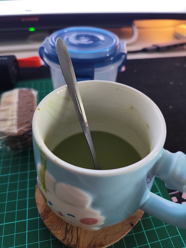 A photograph of a homemade matcha drink in a glass on a wooden table.