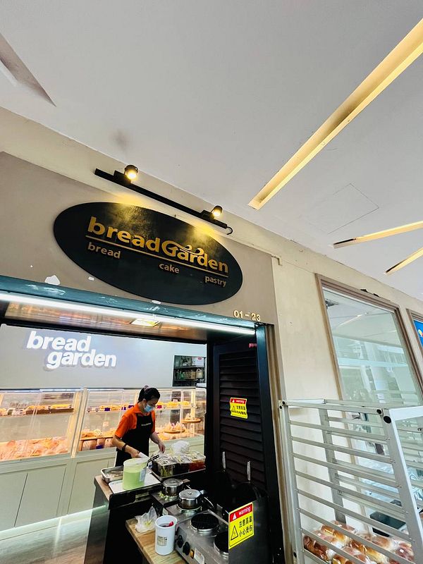 A bakery named 'breadGarden' is depicted, showcasing a staff member preparing food.