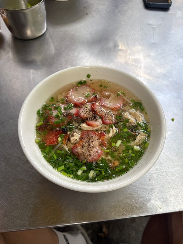 A bowl of Vietnamese noodle soup garnished with various toppings.