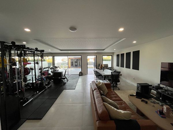 A spacious, modern room featuring a gym area and a work space.