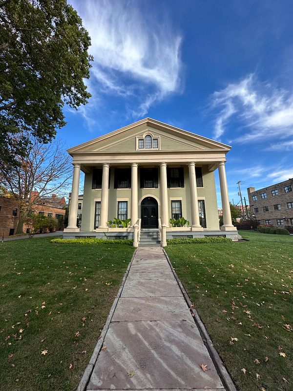 A historic building with a grand facade and lush green surroundings.