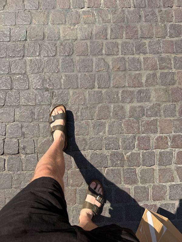 A pair of brown leather Birkenstock sandals placed on a dark cloth surface.