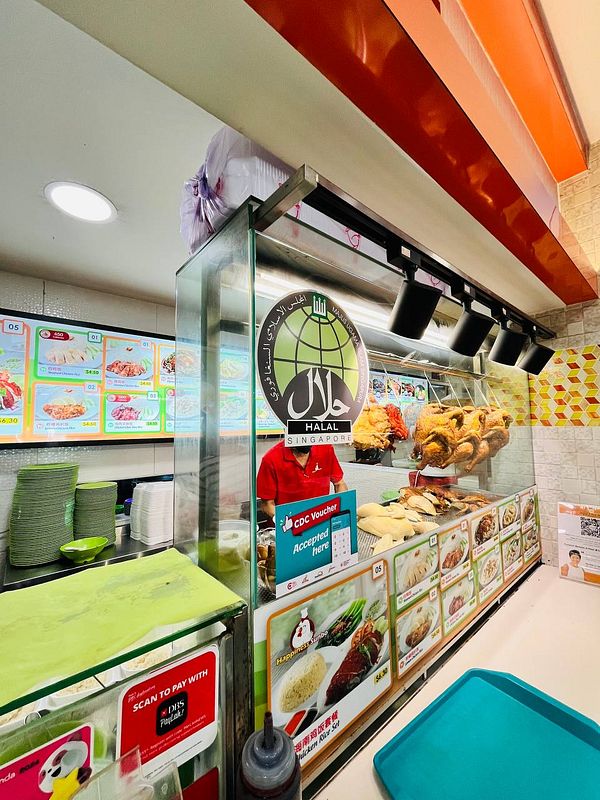 A food stall displaying a variety of dishes, prominently featuring chicken rice.