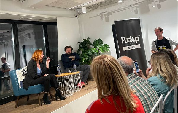 A panel discussion at the Fuckup Nights event in Madrid featuring two speakers and an engaged audience.