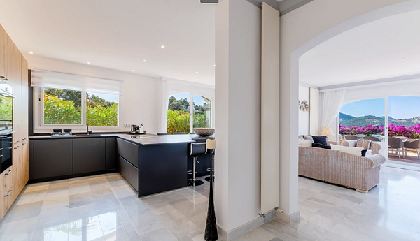 A modern kitchen and living area with large windows showcasing a scenic view.