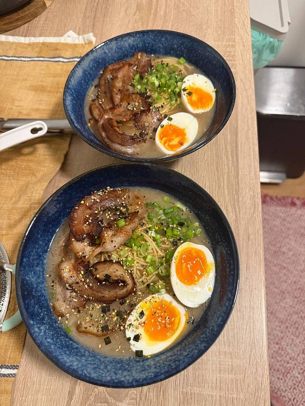 Two bowls of homemade ramen featuring pork, soft-boiled eggs, and green onions.