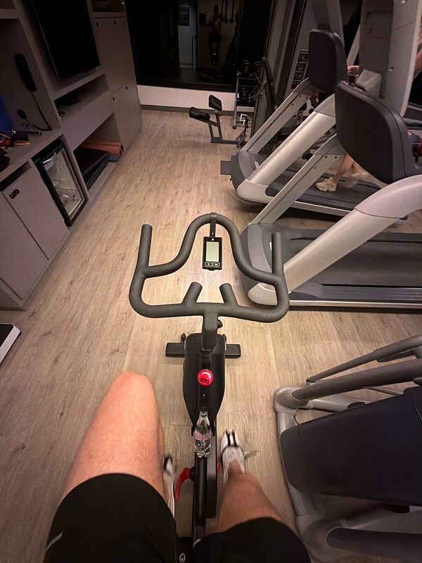 A man lifting a heavy metal dumbbell in a gym environment.