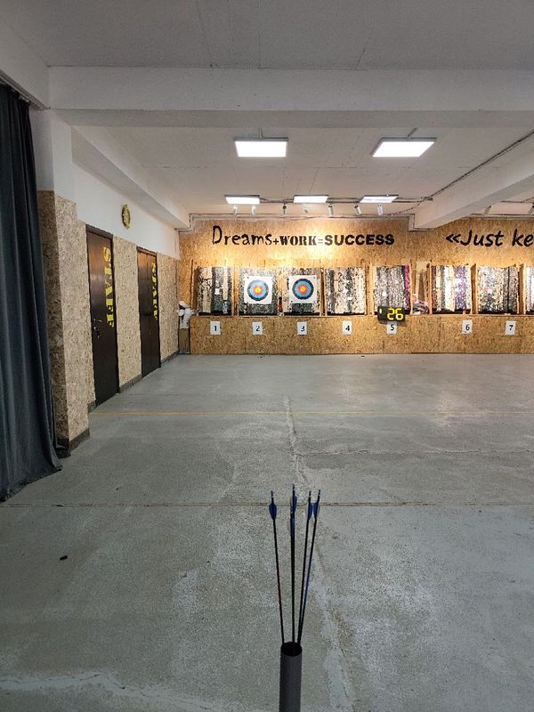 Indoor archery training range with targets and arrows in a quiver in the foreground.