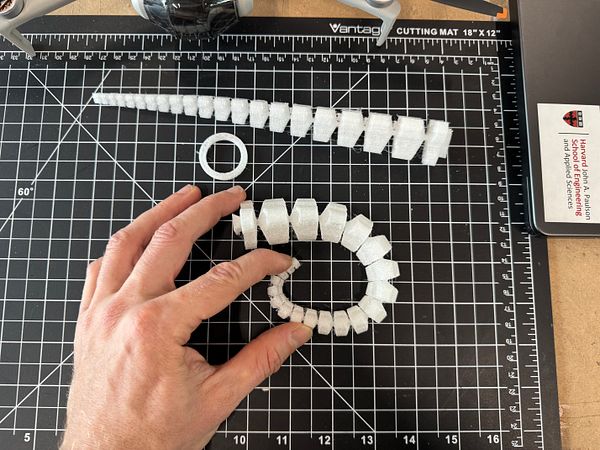 The image displays various 3D-printed tentacle components on a cutting mat.